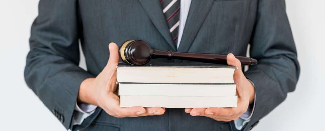 עורך דין ייפוי כח מתמשך - איש מעונב לובש חליפה כהה ומחזיק ספרים.