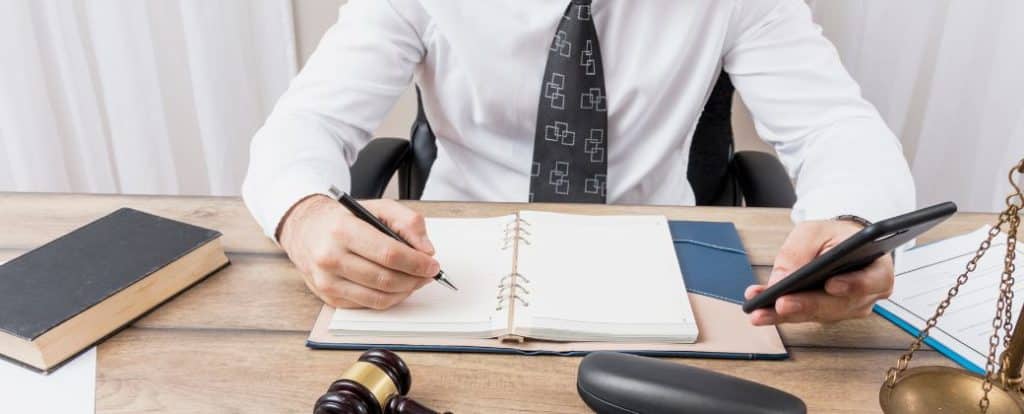 עורך דין ייפוי כח מתמשך לובש חולצה לבנה ועונב עניבה. מחזיק ביד טלפון וביד השייה עט